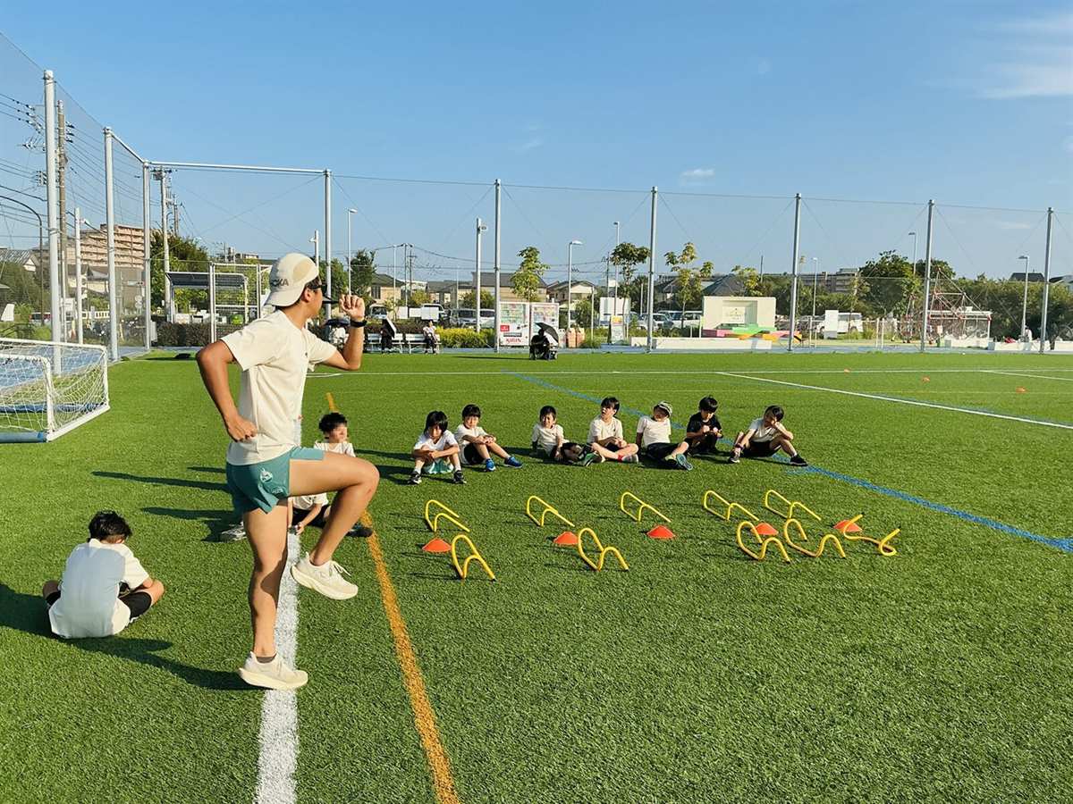 コーチが小学生に走りのフォームを指導している様子